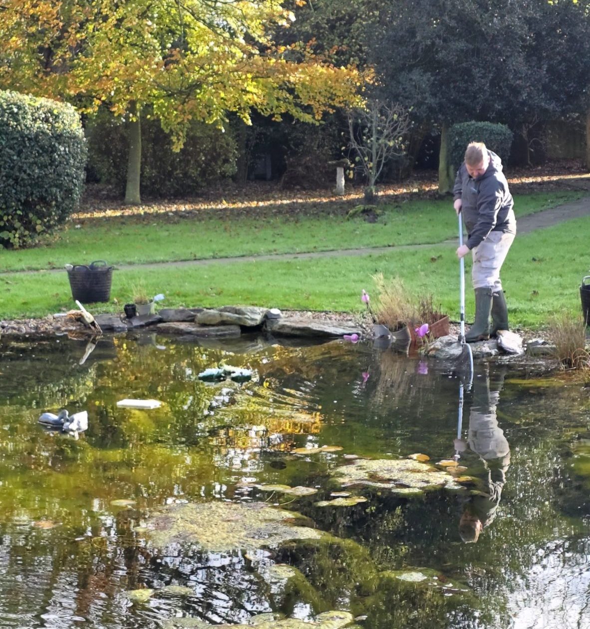 technician carrying out planned pond maintenance visit checking filtration and water flow
